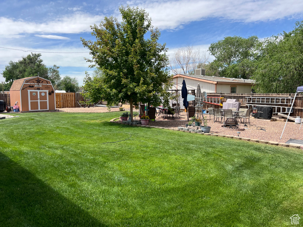 Fenced backyard with a storage unit and a patio area
