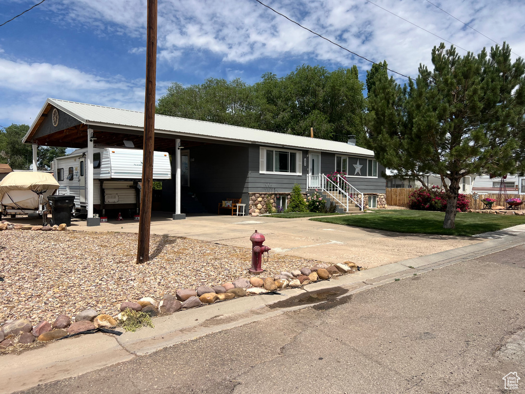View of front of property featuring a carport, a front lawn, and driveway