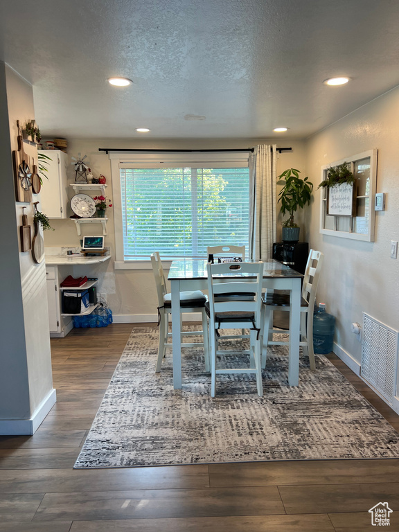 Dining room with dark wood-style flooring, recessed lighting, and a textured ceiling