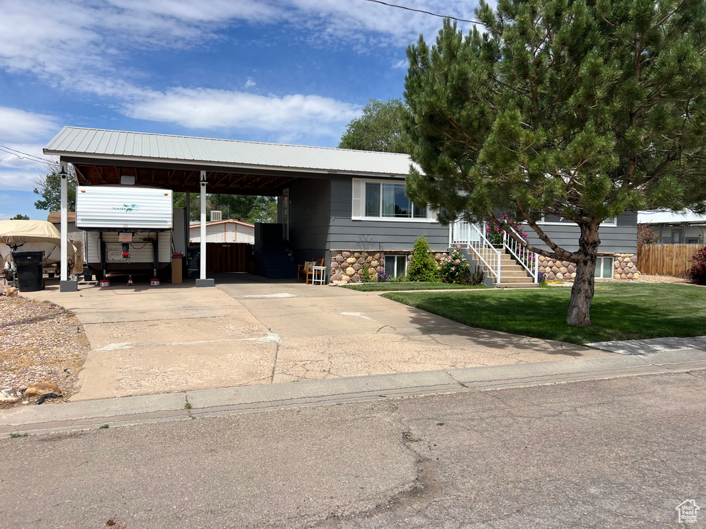 View of front of home with driveway, a metal roof, and an attached carport