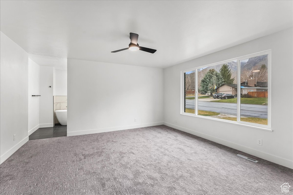 Unfurnished bedroom featuring carpet flooring, ensuite bathroom, and a ceiling fan