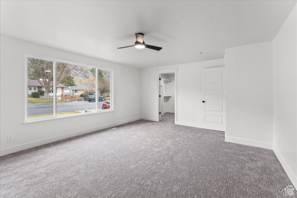 Unfurnished bedroom with carpet floors, a spacious closet, and ceiling fan