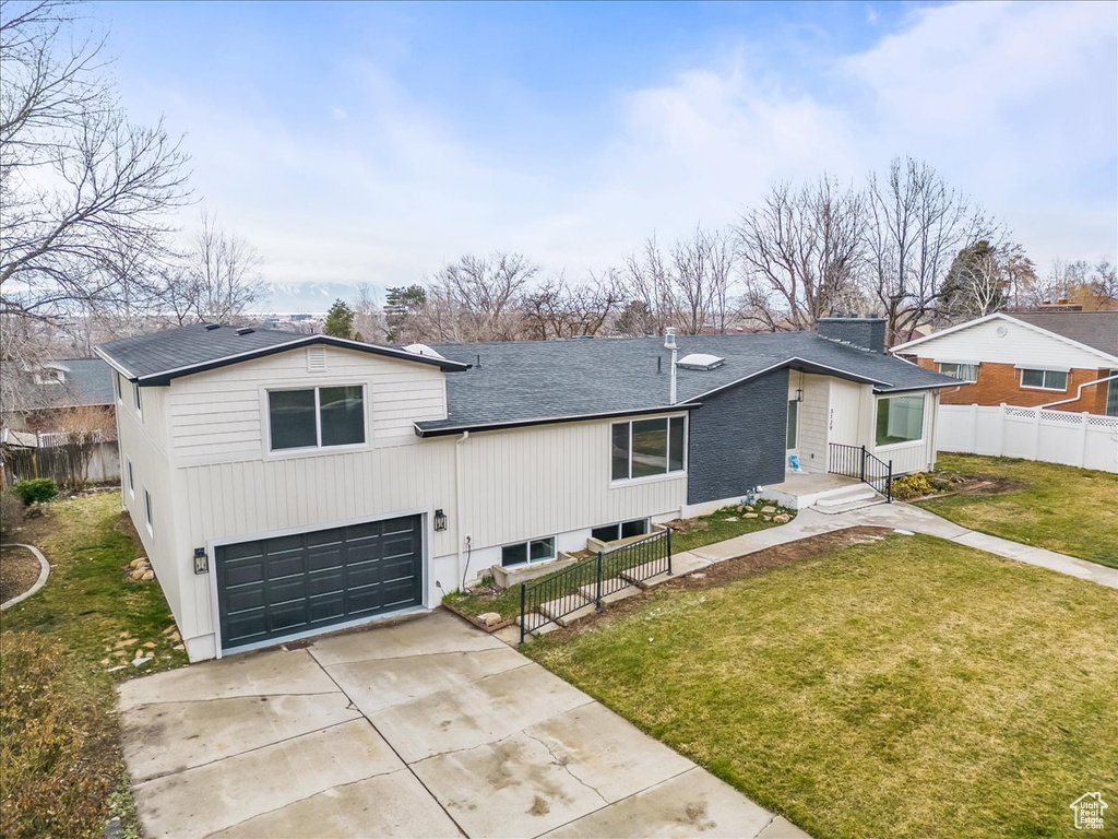 View of front of house featuring a garage, concrete driveway, and a shingled roof