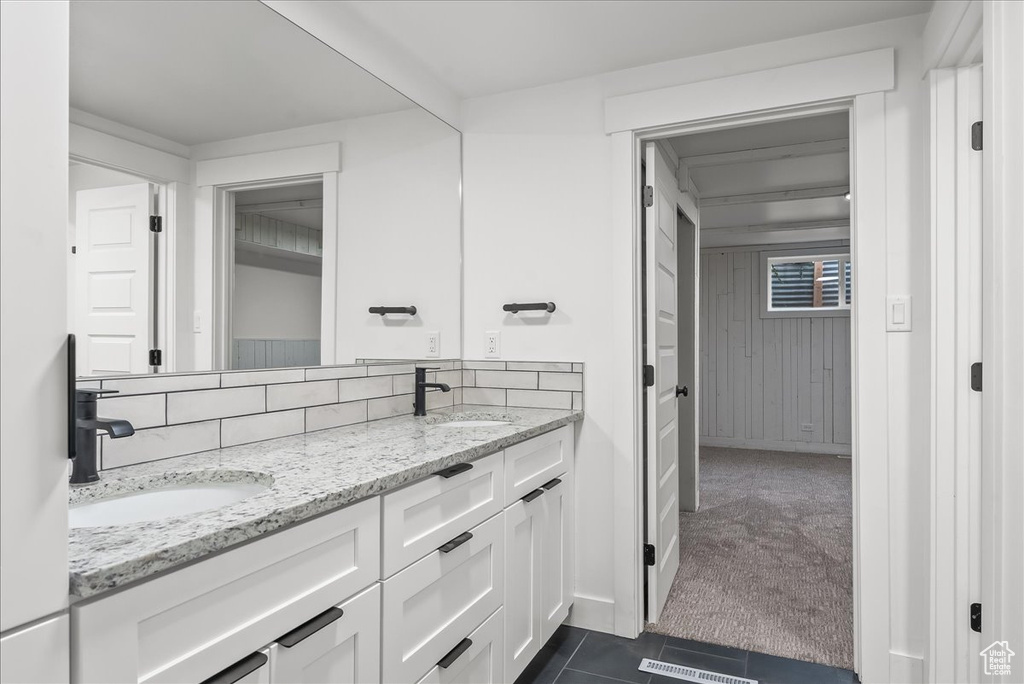 Bathroom featuring double vanity, tile patterned flooring, and decorative backsplash