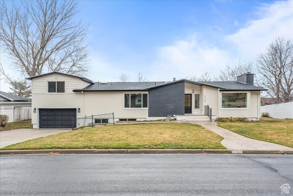 View of front of house featuring a garage, a chimney, and driveway