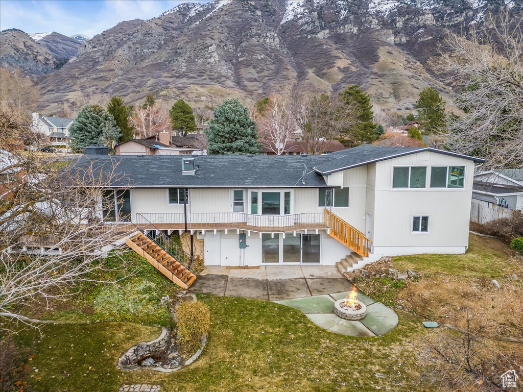 Back of property featuring a patio, stairway, a deck with mountain view, and a fire pit