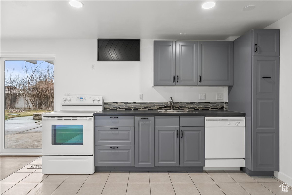 Kitchen featuring white appliances, gray cabinetry, dark countertops, light tile patterned floors, and recessed lighting