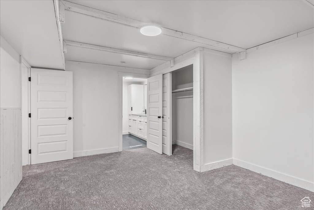 Unfurnished bedroom featuring carpet flooring, a closet, and ensuite bath