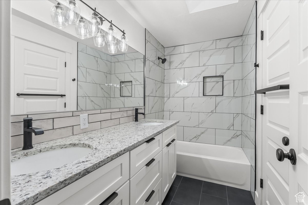 Bathroom featuring tile patterned floors, double vanity, bathing tub / shower combination, tile walls, and decorative backsplash