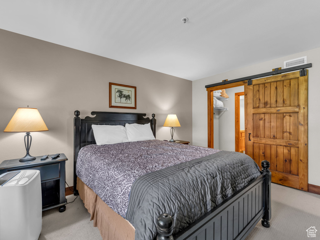 Bedroom featuring light carpet, a spacious closet, and a closet