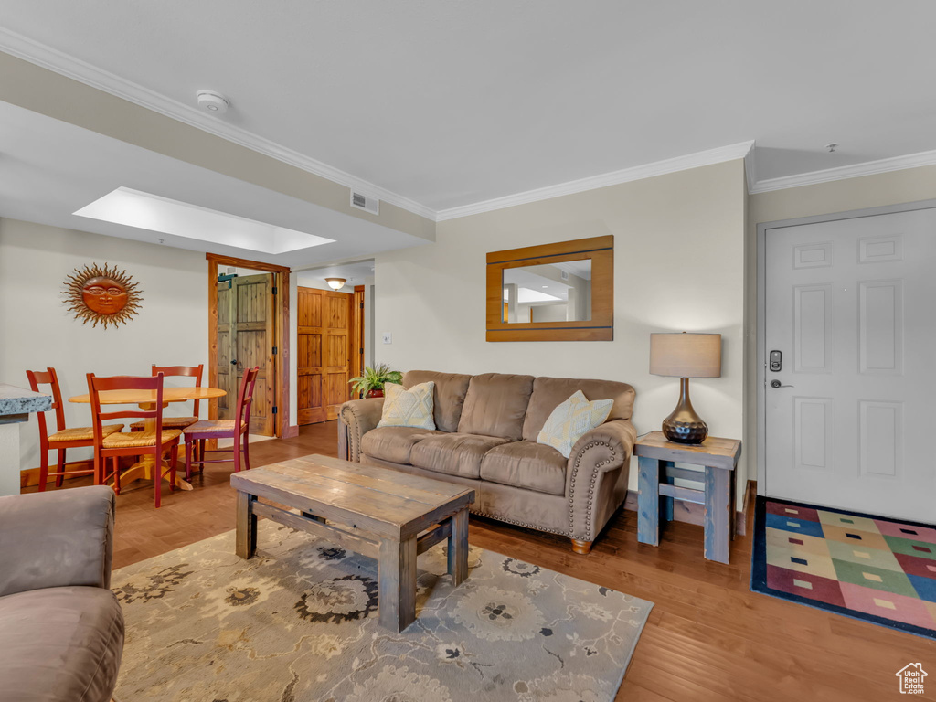 Living area with crown molding and wood finished floors