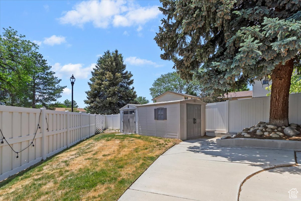 Fenced backyard featuring a shed and a patio area