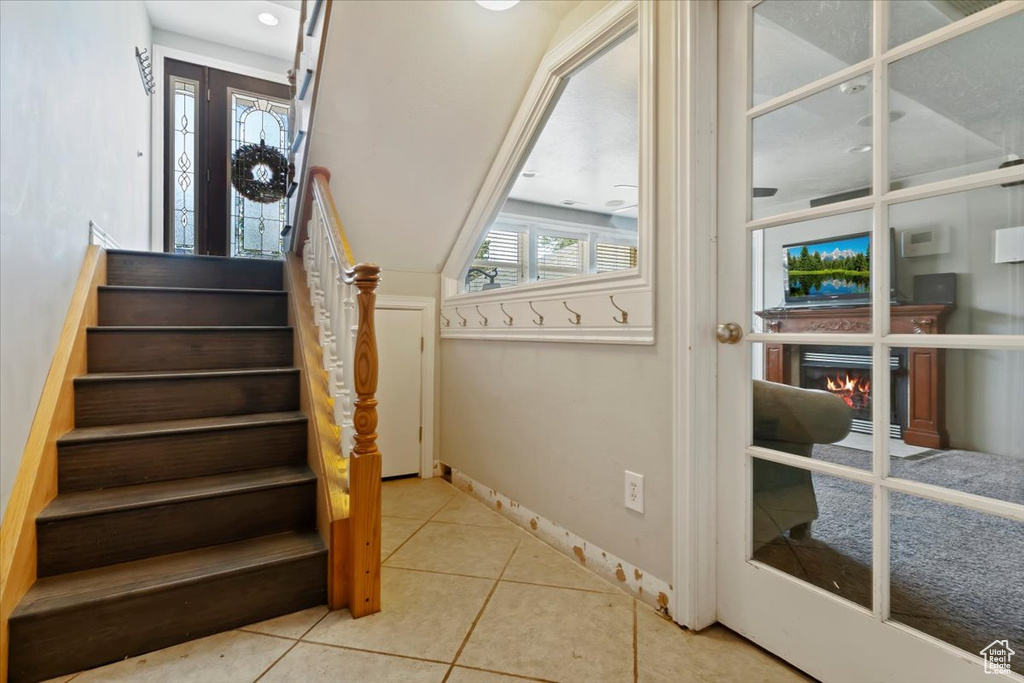 Stairway with tile patterned floors and a warm lit fireplace
