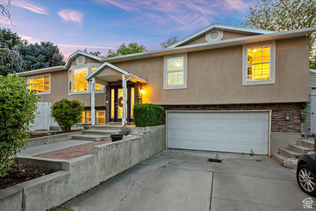 View of front facade with an attached garage, stucco siding, concrete driveway, and stone siding