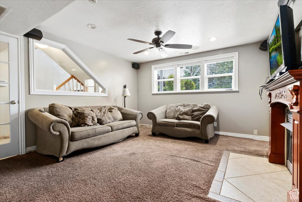 Living area with light colored carpet, a ceiling fan, a textured ceiling, and recessed lighting