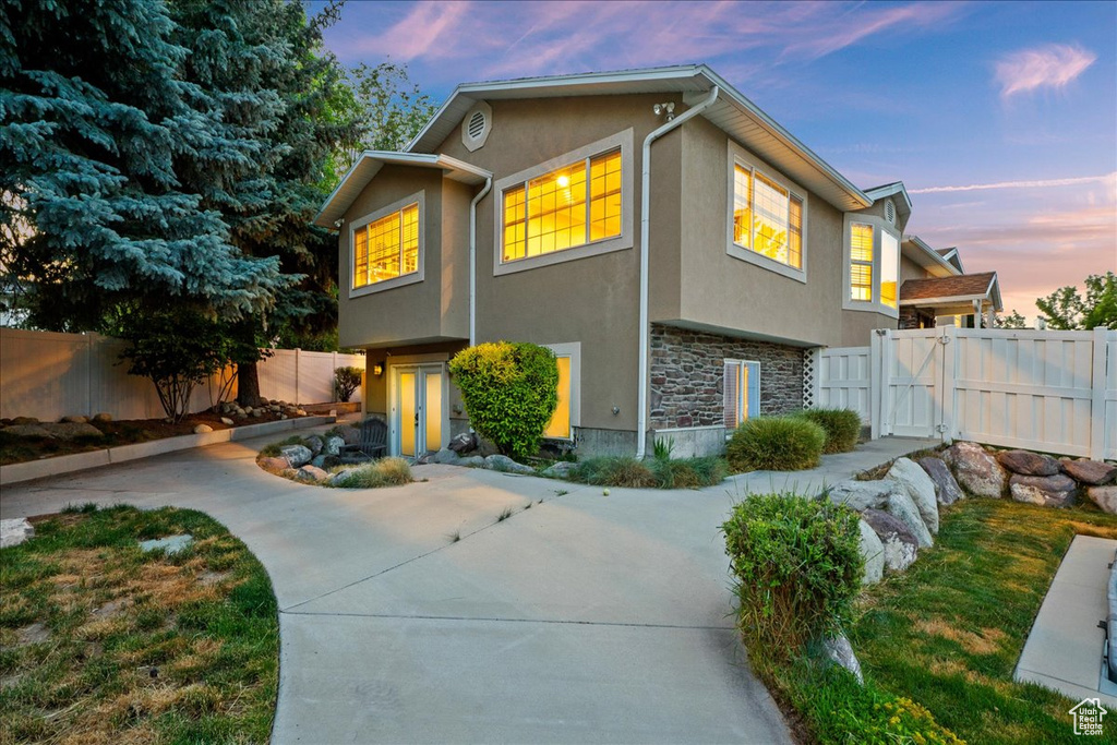 View of front of property with stone siding, stucco siding, and a fenced backyard