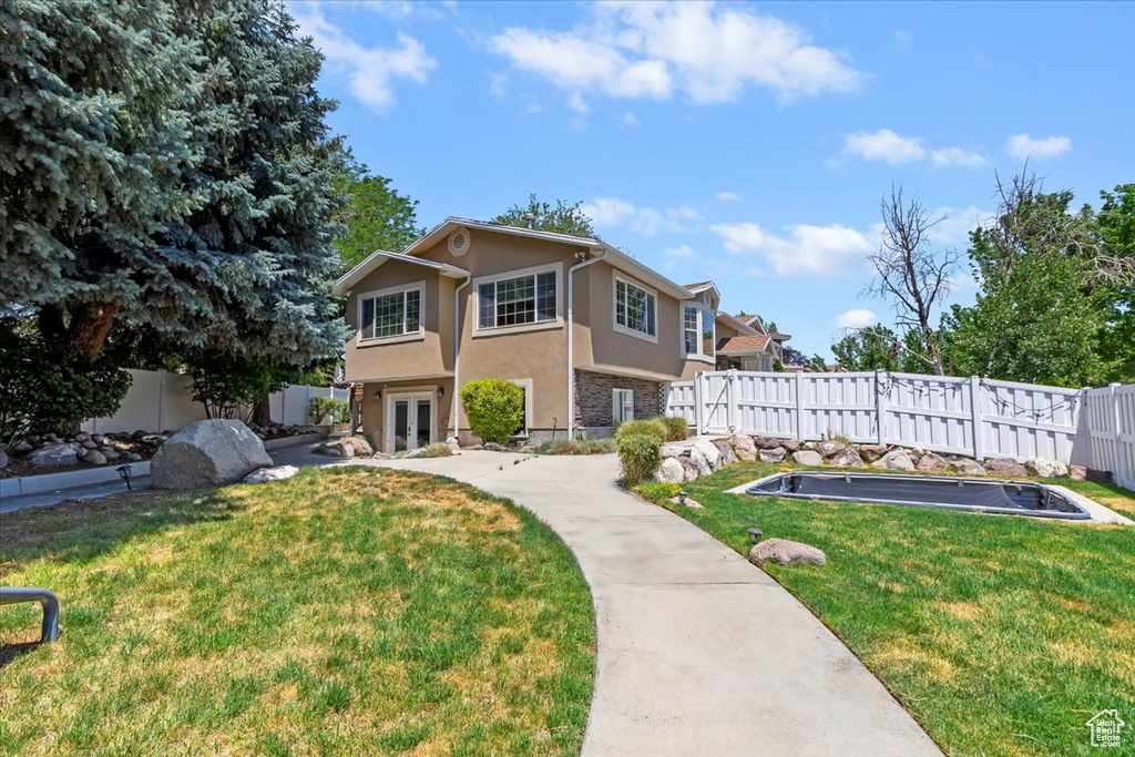 View of front of home with stucco siding, french doors, and a fenced backyard