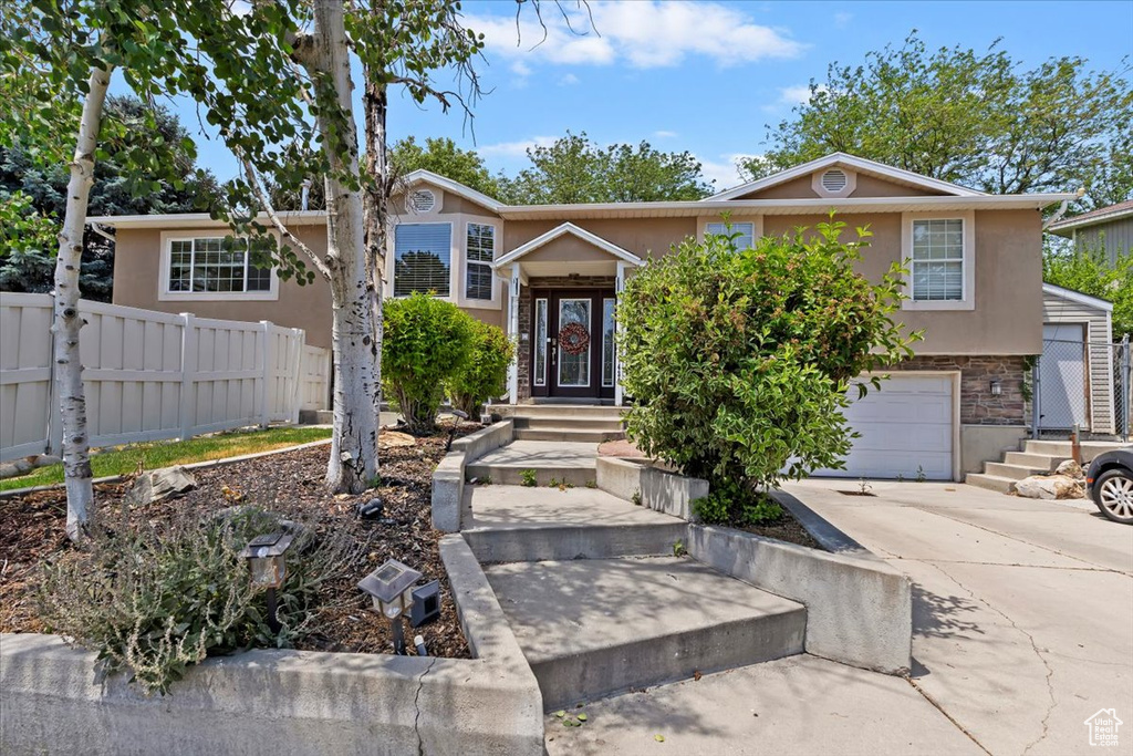 View of front of home featuring stucco siding, a garage, concrete driveway, and stone siding