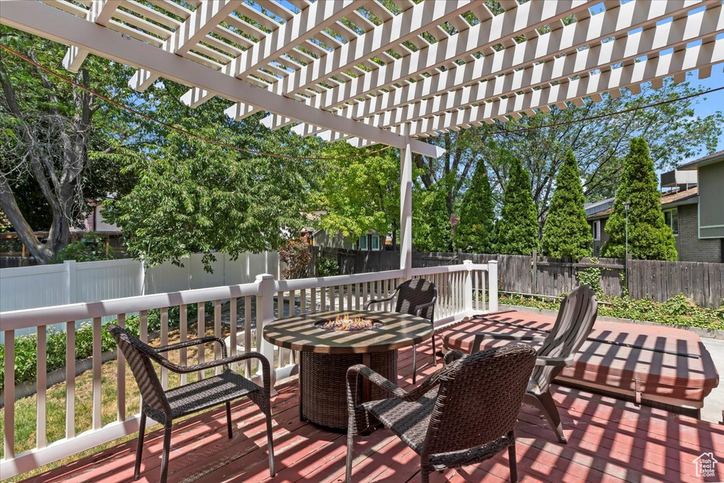 Wooden terrace with a fenced backyard and a pergola