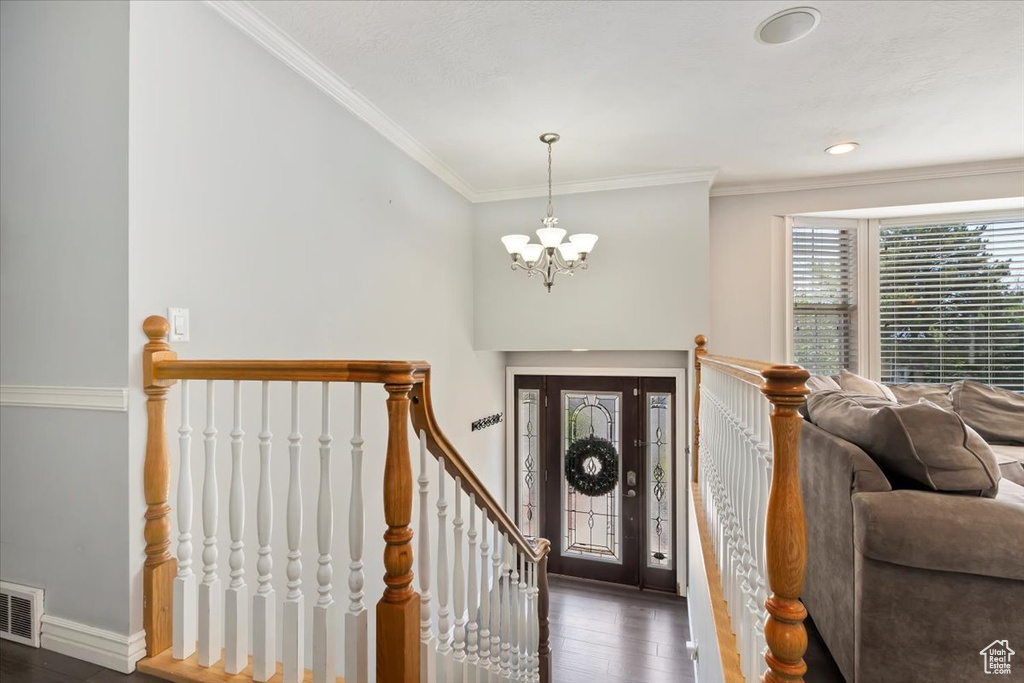 Entryway with a chandelier, dark wood-style floors, and crown molding