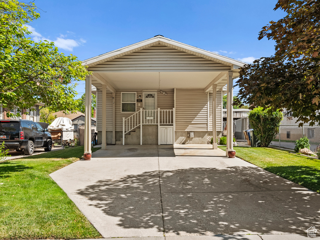View of front of home with a front lawn, driveway, and a carport