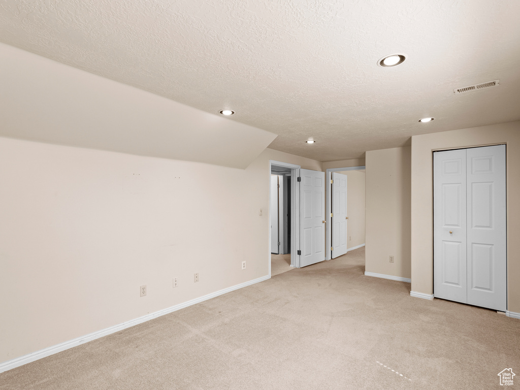 Unfurnished bedroom with light colored carpet, recessed lighting, a textured ceiling, and a closet