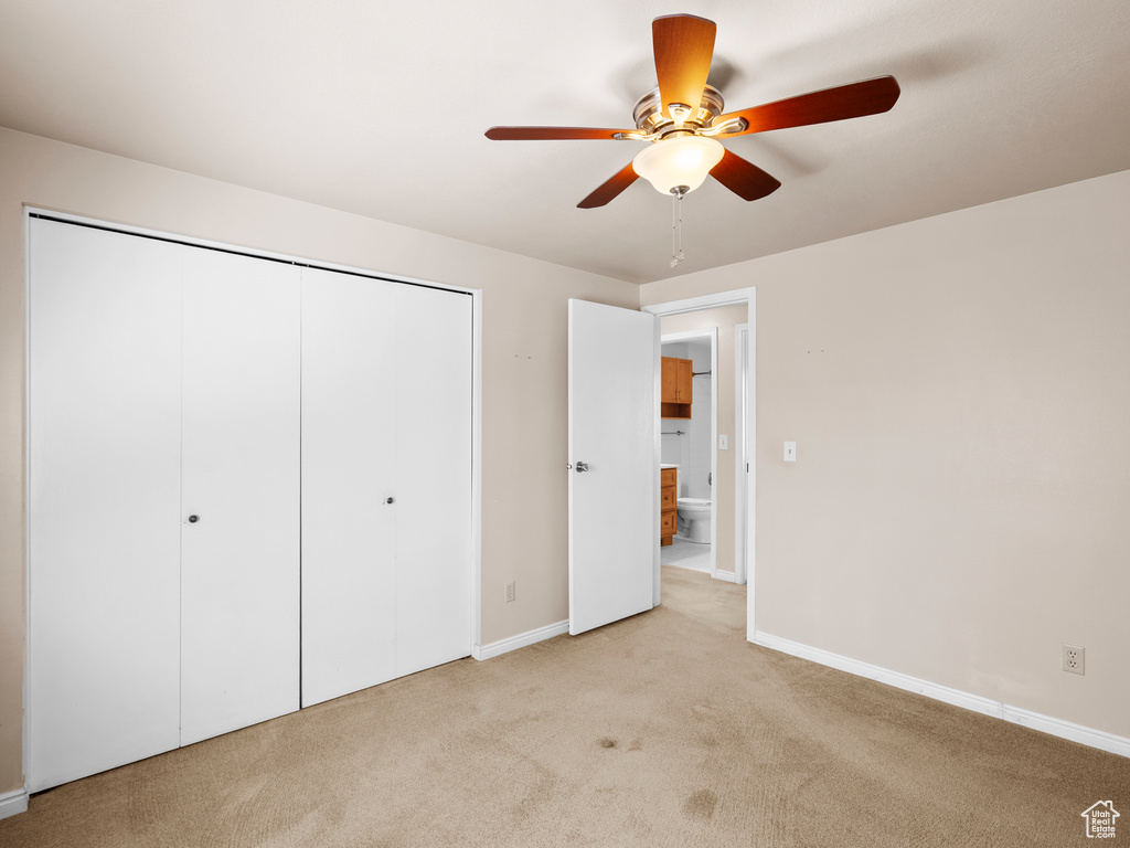 Unfurnished bedroom with light colored carpet, a closet, and a ceiling fan