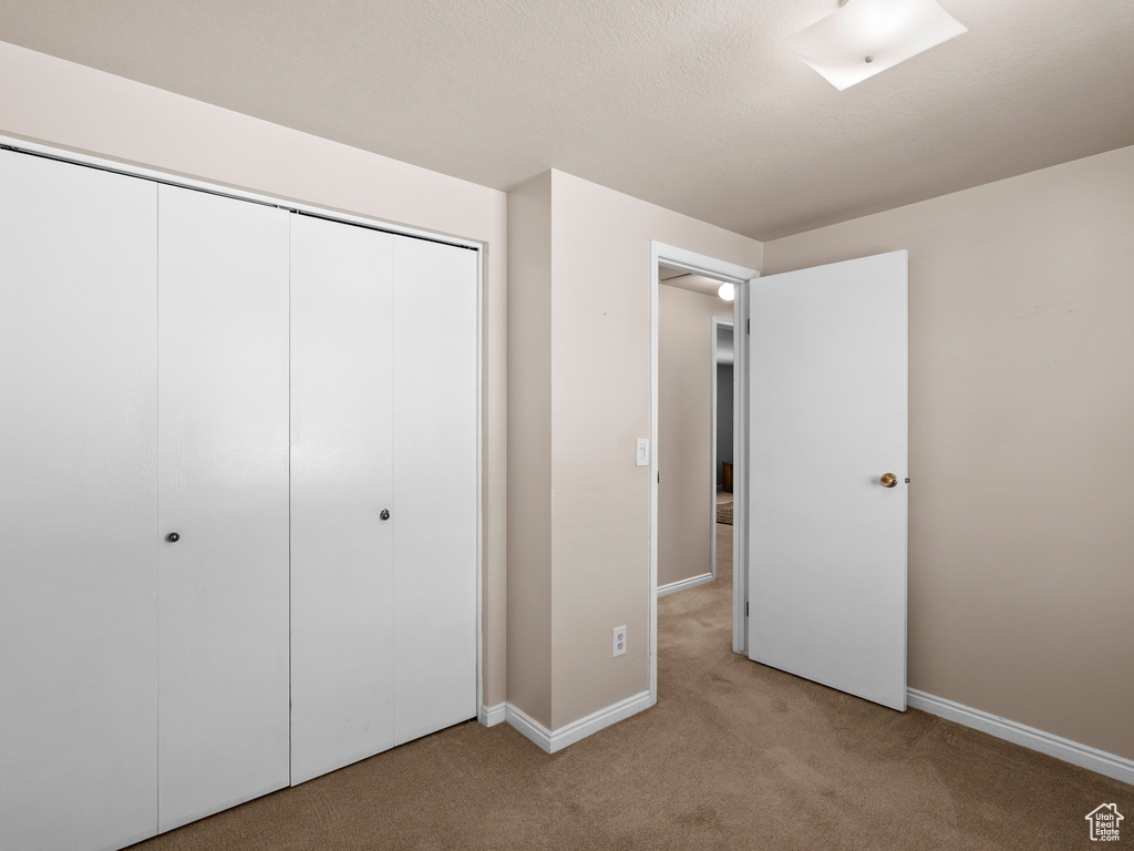 Unfurnished bedroom featuring light colored carpet and a closet