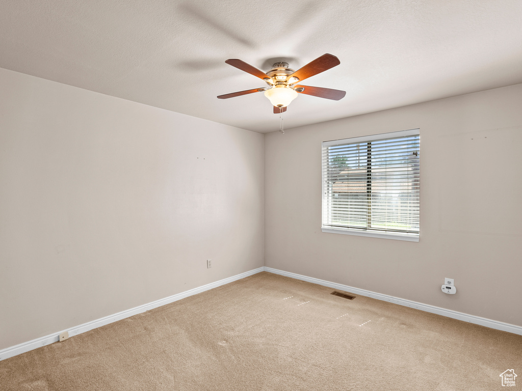 Spare room with light carpet and a ceiling fan