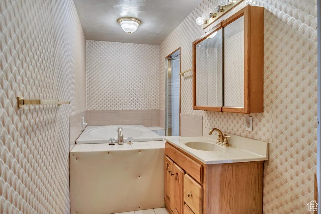 Full bath with wallpapered walls, vanity, a bath, and tile patterned flooring