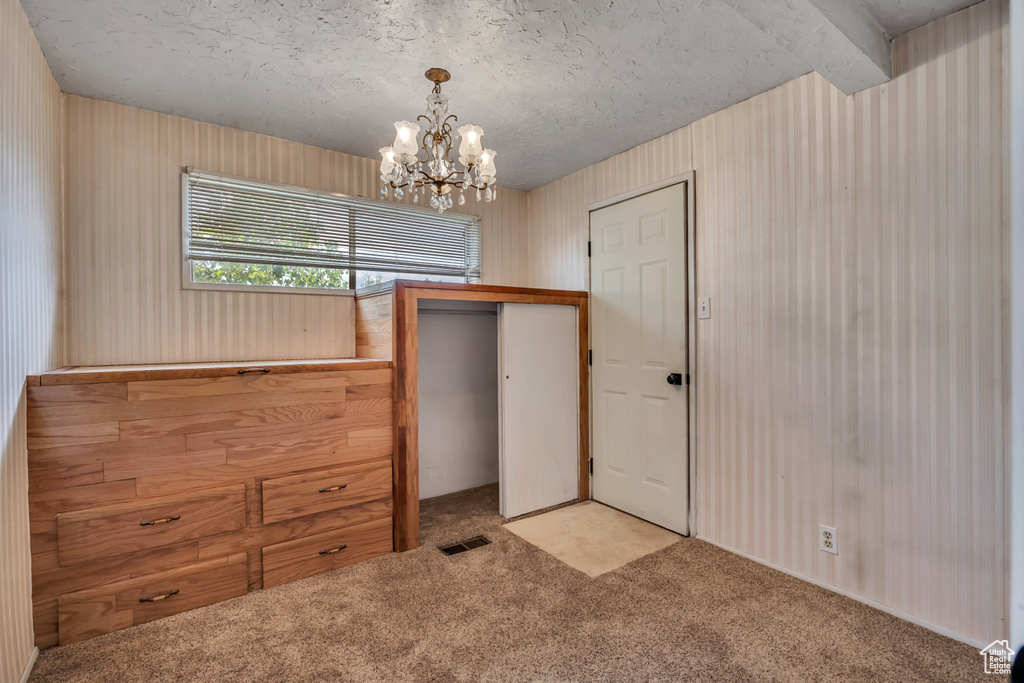 Unfurnished bedroom with carpet flooring, a chandelier, a closet, and a textured ceiling