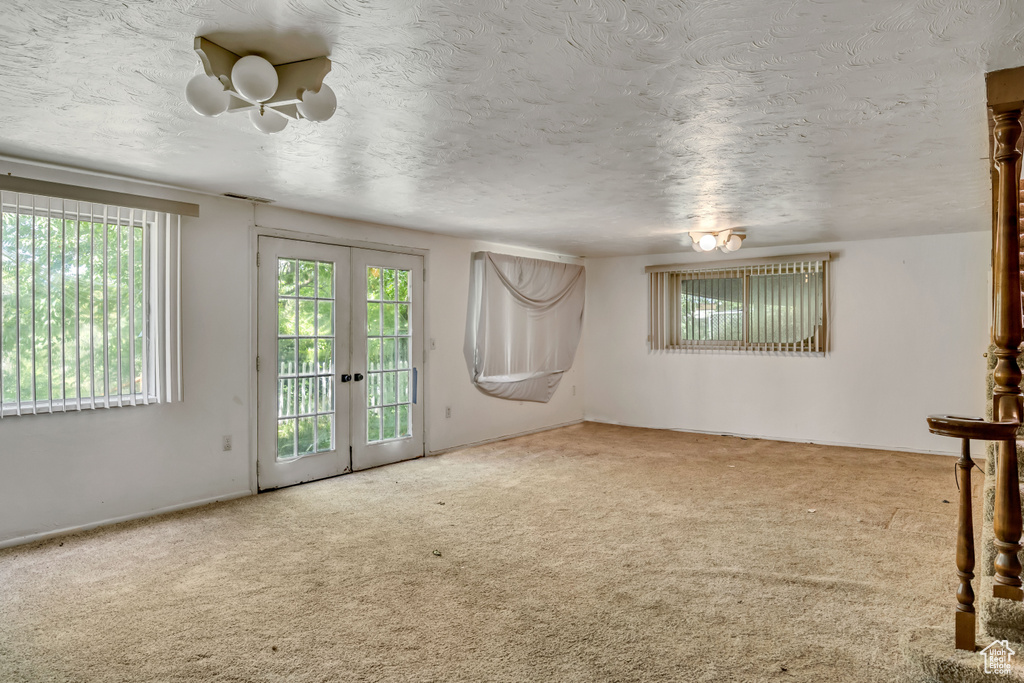Unfurnished room featuring carpet, french doors, and a textured ceiling