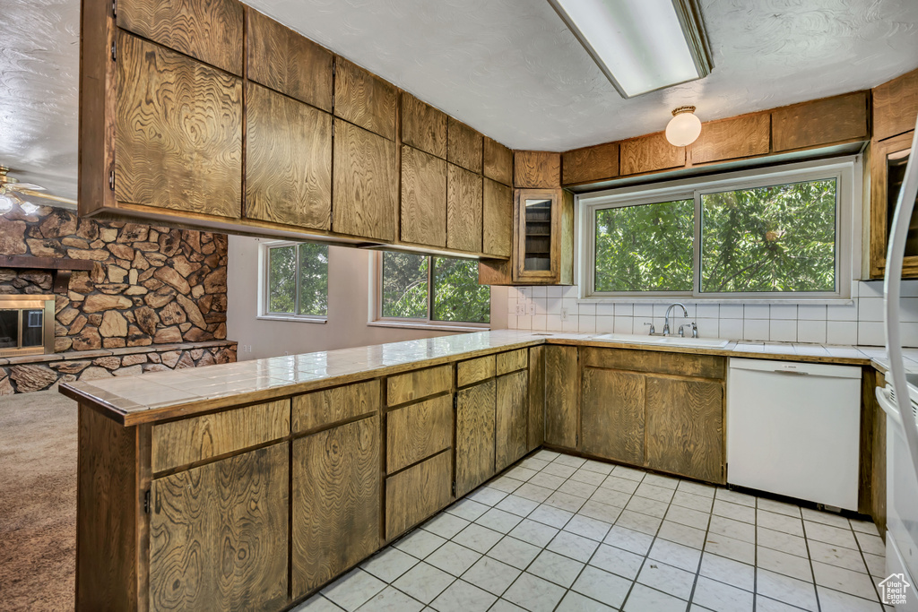 Kitchen with white dishwasher, healthy amount of natural light, light tile patterned flooring, and tasteful backsplash