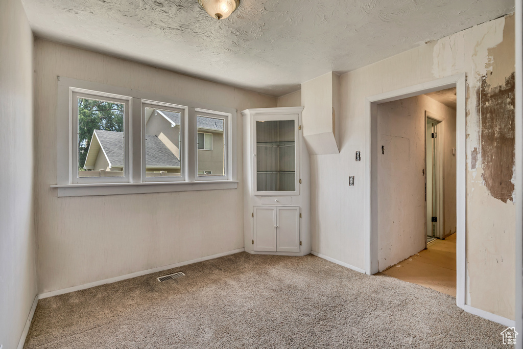 Carpeted spare room featuring baseboards and a textured ceiling