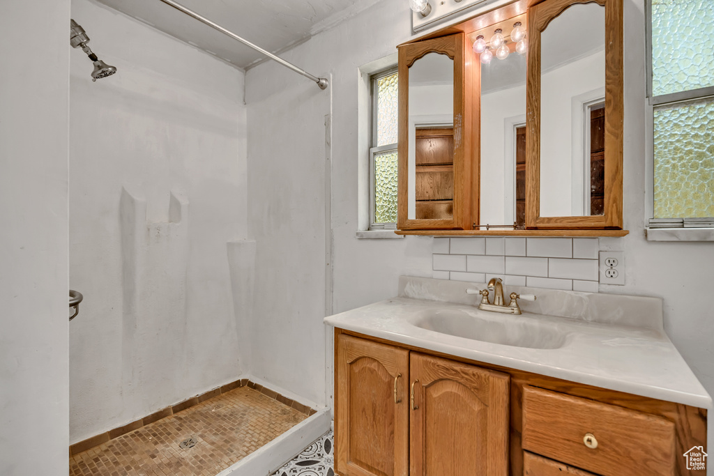 Full bathroom featuring vanity, a shower, backsplash, and crown molding