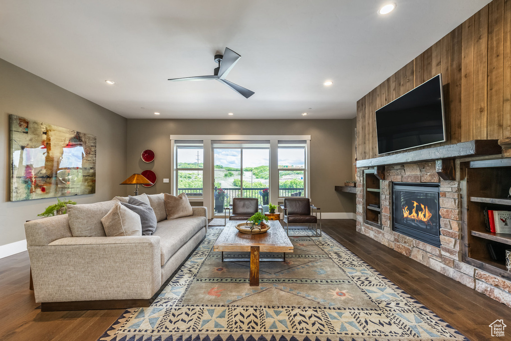 Living area with ceiling fan, wood finished floors, a fireplace, recessed lighting, and wood walls