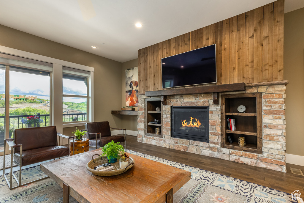 Living area with wood finished floors, recessed lighting, wood walls, and a stone fireplace