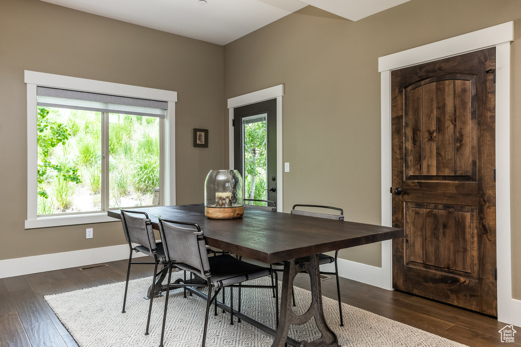 Dining space with dark wood-style flooring and baseboards