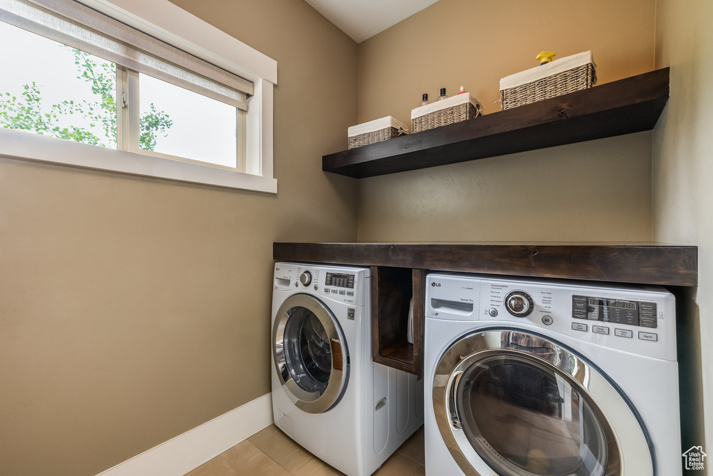 Laundry area featuring washing machine and clothes dryer and light tile patterned flooring