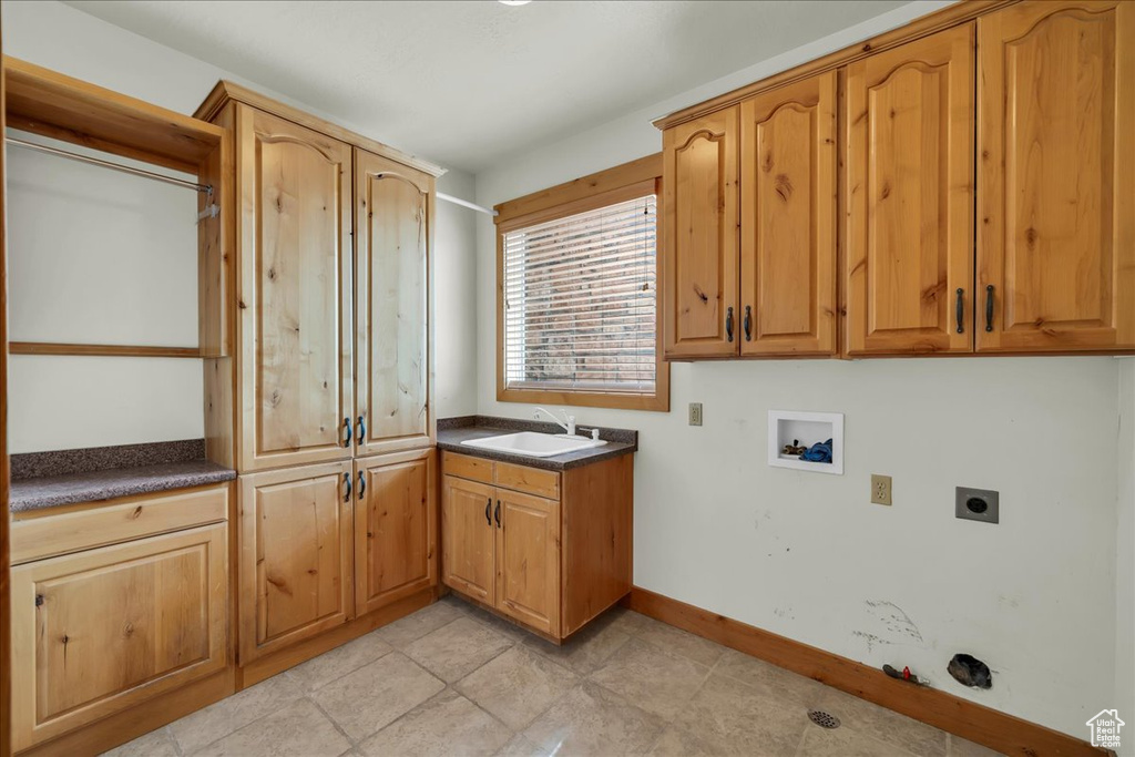 Washroom with hookup for an electric dryer, cabinet space, hookup for a washing machine, and light tile patterned floors