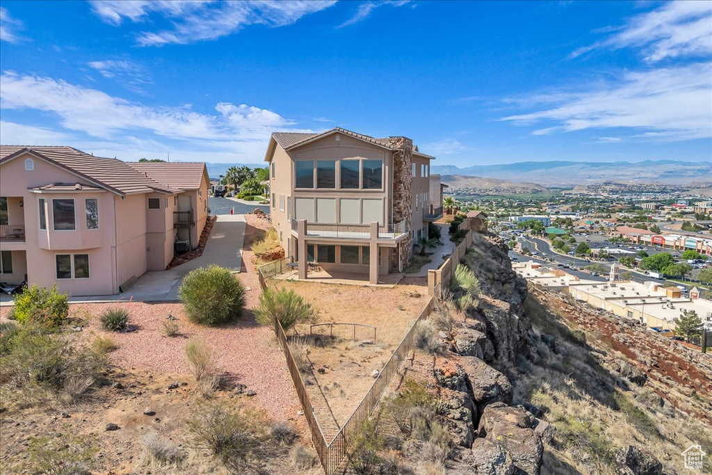 Rear view of property with stucco siding, a mountain view, and a tiled roof