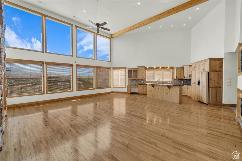 Unfurnished living room with high vaulted ceiling, ceiling fan, light wood finished floors, beam ceiling, and recessed lighting