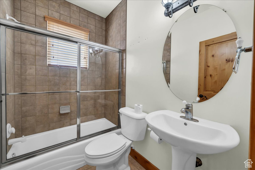 Bathroom featuring combined bath / shower with glass door and toilet