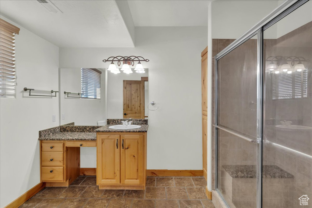 Bathroom with a shower stall, vanity, plenty of natural light, and stone finish flooring