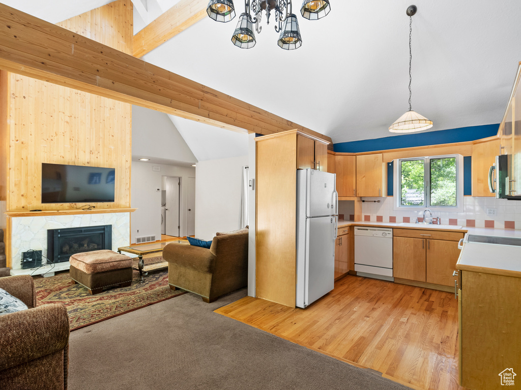 Kitchen with white appliances, open floor plan, light countertops, and hanging light fixtures