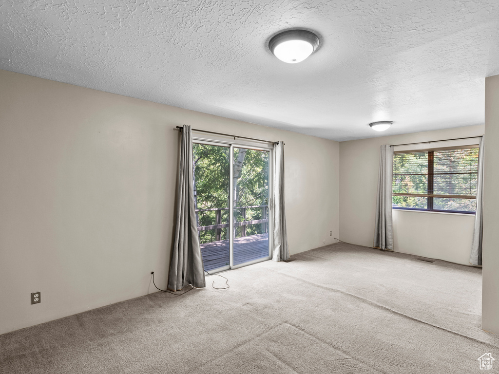 Empty room with light carpet and a textured ceiling