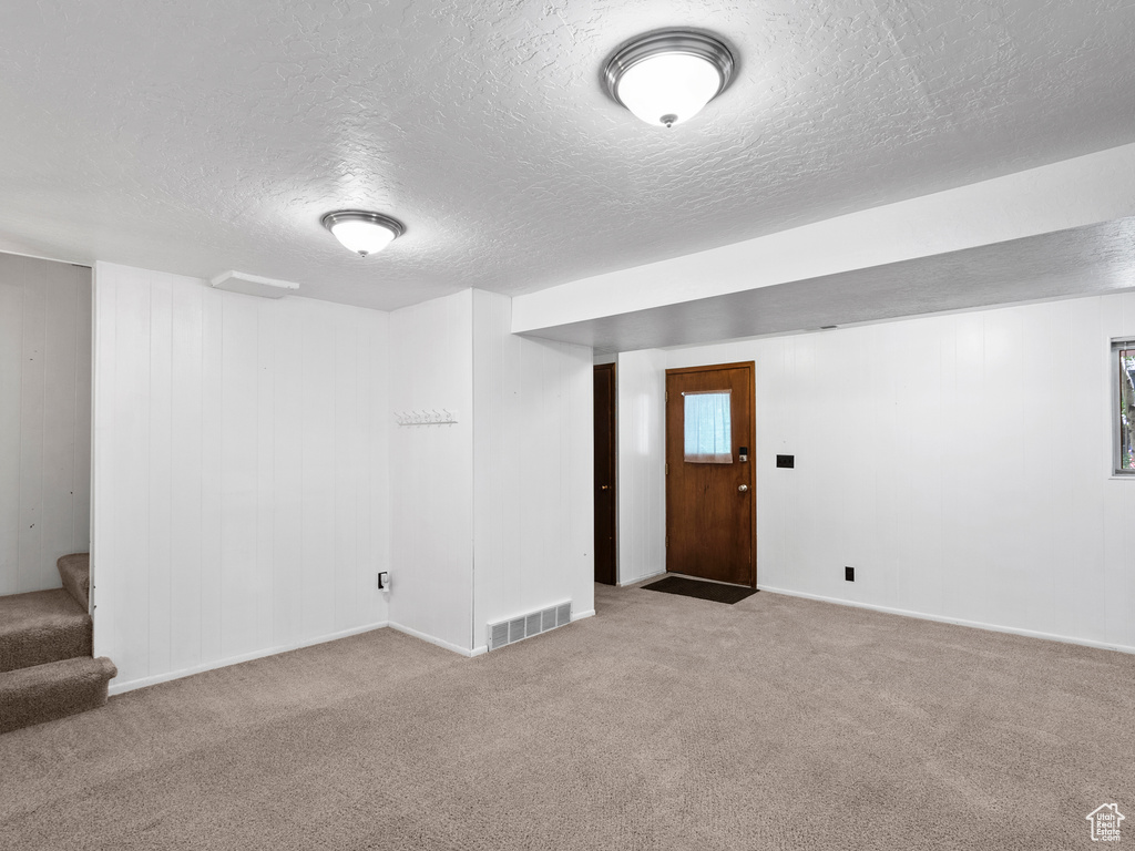 Below grade area featuring carpet floors, a textured ceiling, and stairs