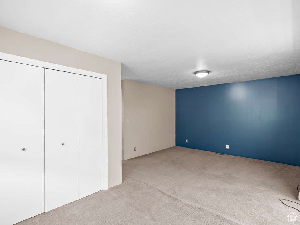 Unfurnished bedroom featuring light carpet and a closet