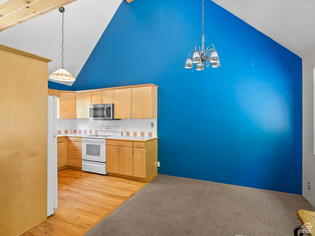 Kitchen with white appliances, light brown cabinets, high vaulted ceiling, decorative backsplash, and a chandelier