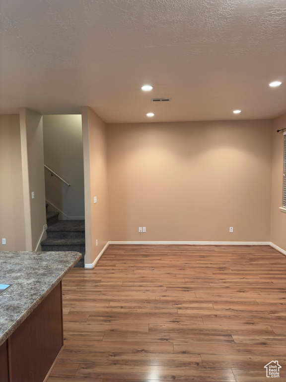 Spare room featuring wood finished floors, recessed lighting, and stairs